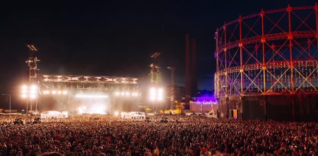 Ihmismassa Flow Festival 2024 -tapahtumassa illalla, yleisö kuuntelee live-keikkaa festivaalialueen päälavalla
