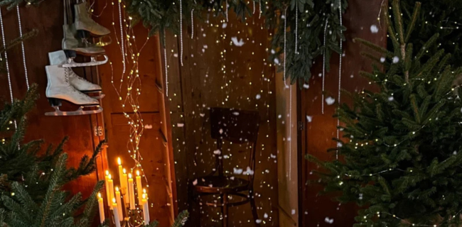 Tunnelmallinen joulukuvausmiljöö, joulukuusia ja luistimet ripustettuna naulaan.