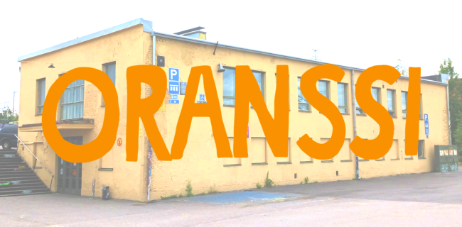 Oranssin logo suvilahden keltaisen rakennuksen päällä