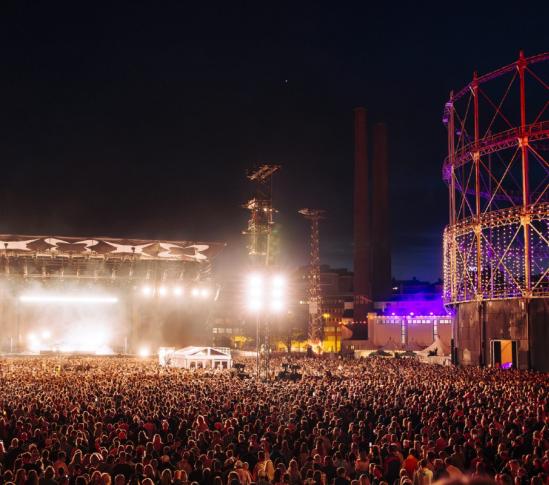 Ihmismassa Flow Festival 2024 -tapahtumassa illalla, yleisö kuuntelee live-keikkaa festivaalialueen päälavalla